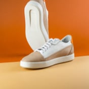 picture of a white and beige pair of shoes in a dark orange background